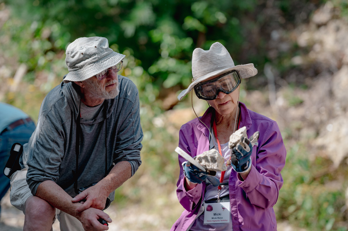 people inspecting rock specimens at maine pegmatite workshop