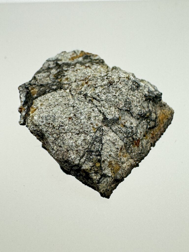 Close-up of a Peekskill meteorite specimen showing its textured gray surface and rusty brown patches.