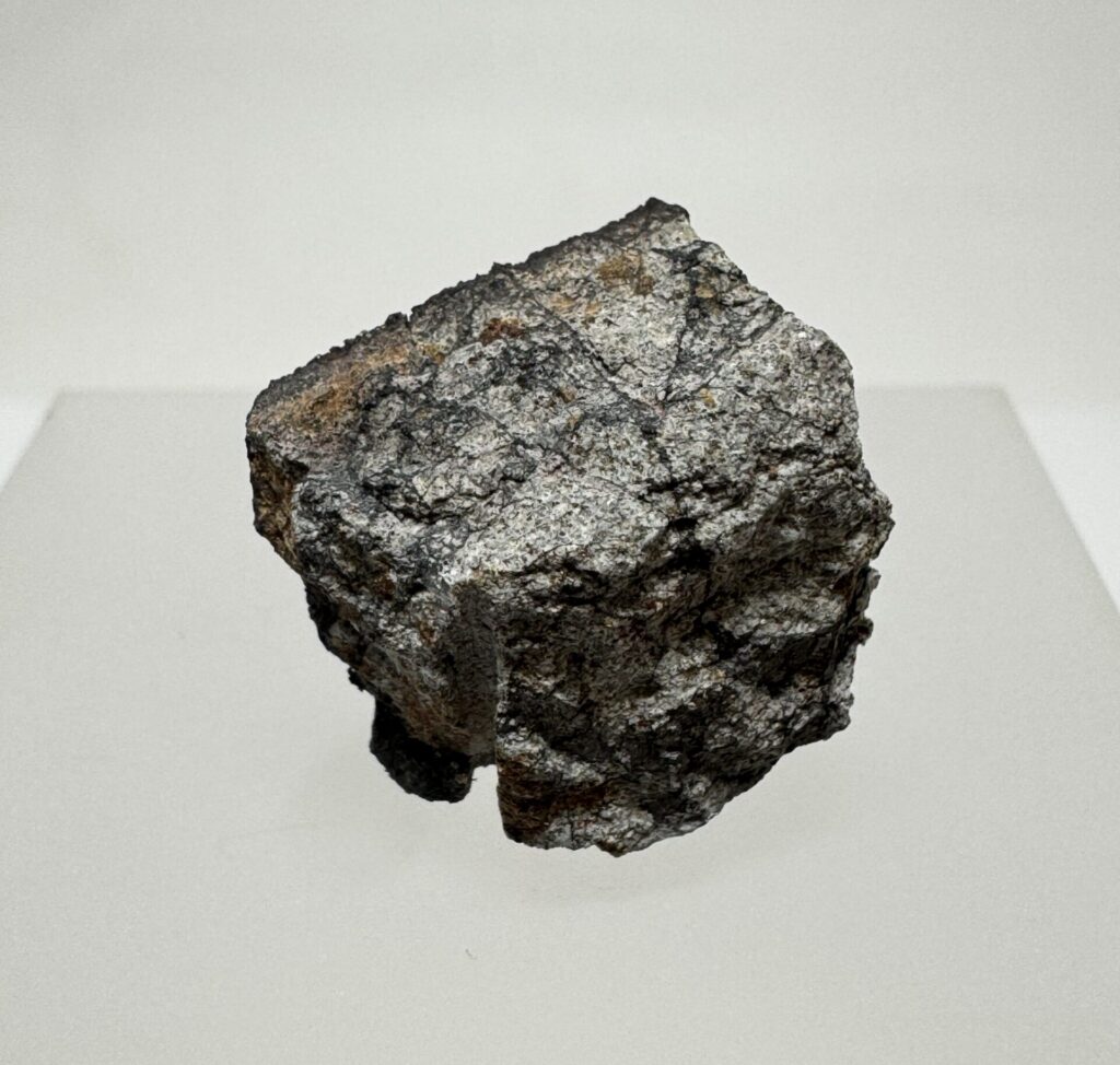 Angular Peekskill meteorite specimen displayed on a light-colored pedestal.