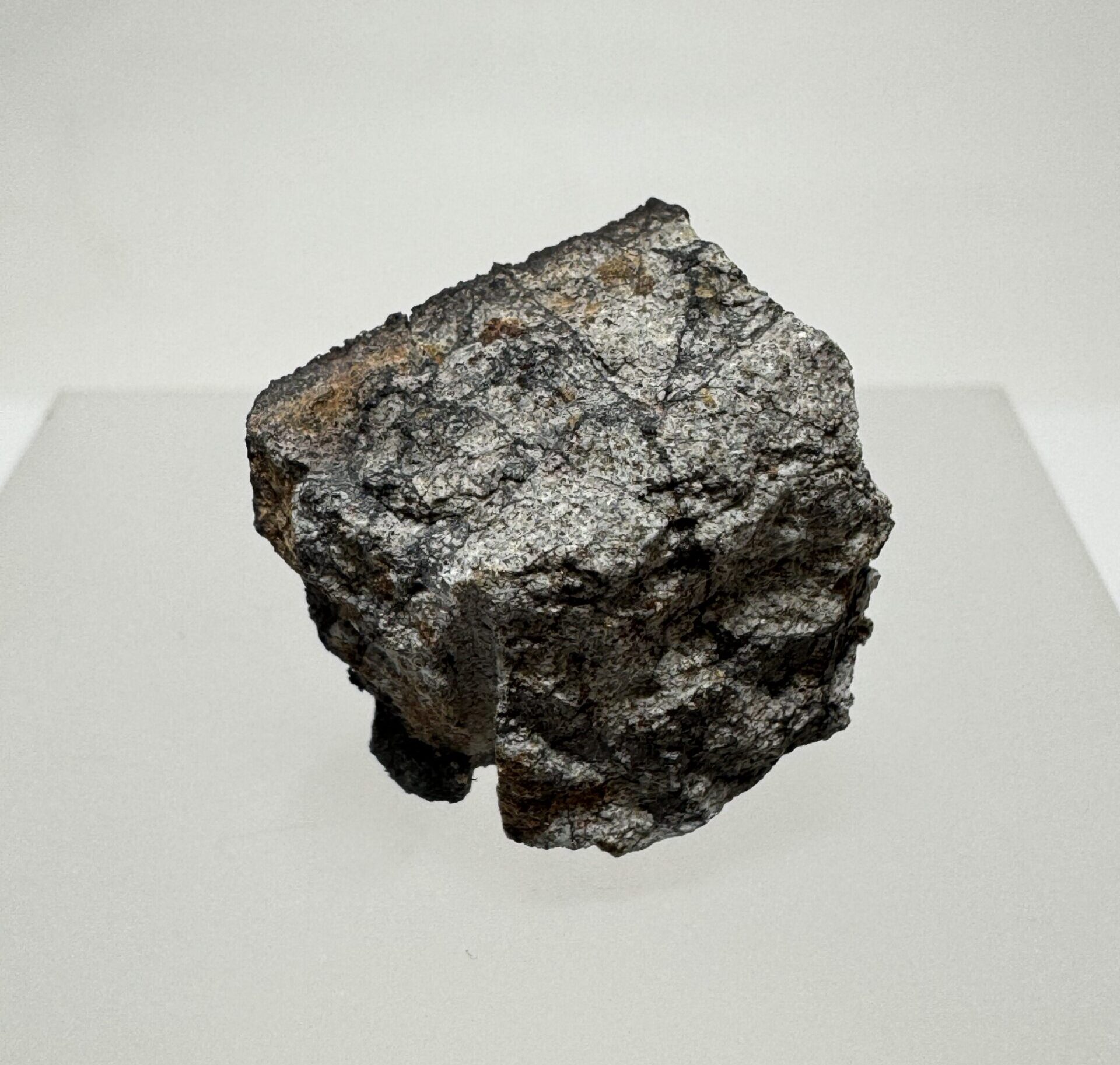 Angular Peekskill meteorite specimen displayed on a light-colored pedestal.